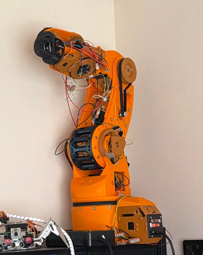 Version One, the orange six-axis arm, standing assembled on top of a cabinet