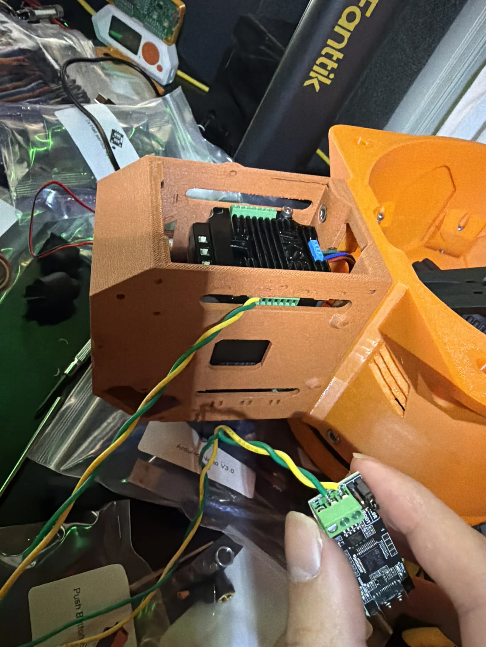 The orange arm base opened up with a driver board and wiring harness inside