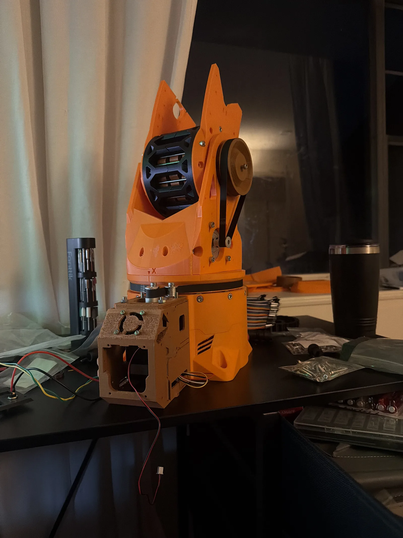 The orange Version One arm standing assembled on a desk