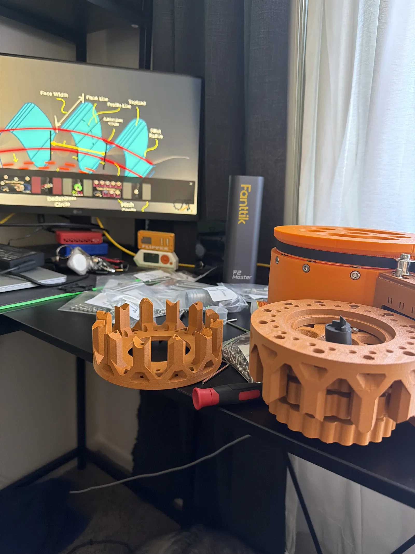 Cycloidal gearbox components laid out on a desk in front of a monitor