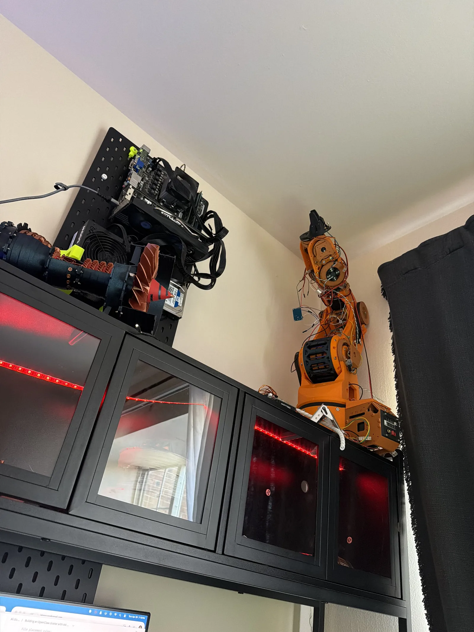 The retired orange arm sitting on a shelf above the workbench