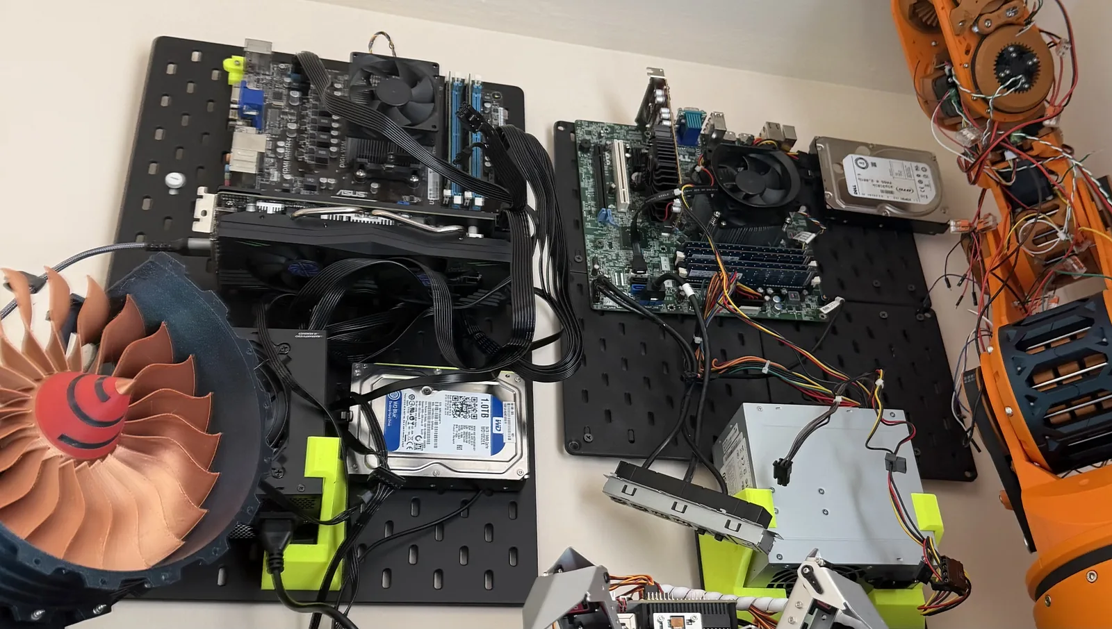 Compute hardware mounted to a pegboard above the bench with a cooling fan